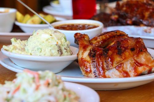 A plate featuring grilled chicken with barbecue sauce, creamy potato salad, and a side of baked beans.