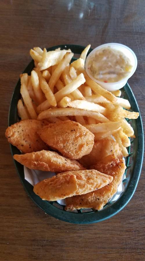 A basket of golden fried chicken tenders, crispy French fries, and a small cup of dipping sauce.