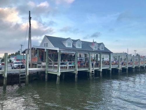 A waterfront restaurant with outdoor seating, surrounded by water and a cloudy sky.