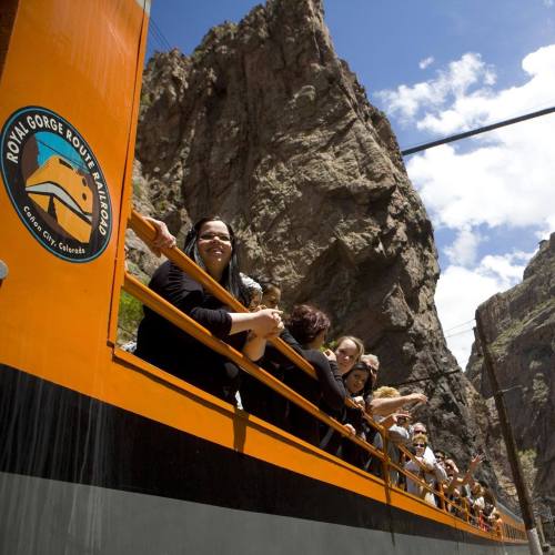 A group of people enjoying a scenic train ride through a rocky gorge on the Royal Gorge Route Railroad in Colorado.