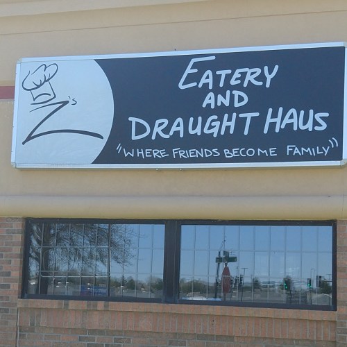 Sign for Z's Eatery and Draught Haus, featuring a chef's hat and the slogan "Where friends become family."