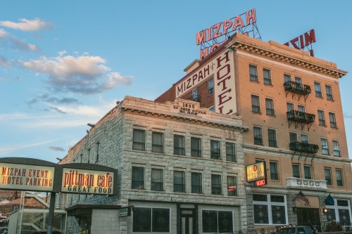 Historic Mizpah Hotel with neon signs, featuring a café and event parking, set against a blue sky.