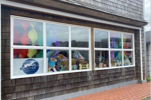 A storefront window displays colorful decorations and plush toys, with an "OPEN" sign visible.