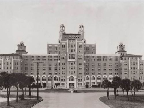 Historic black-and-white photo of a large, ornate hotel building with multiple stories and distinctive architectural features.