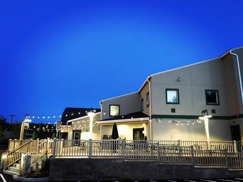 A cozy building with outdoor seating, illuminated by string lights, against a deep blue evening sky.