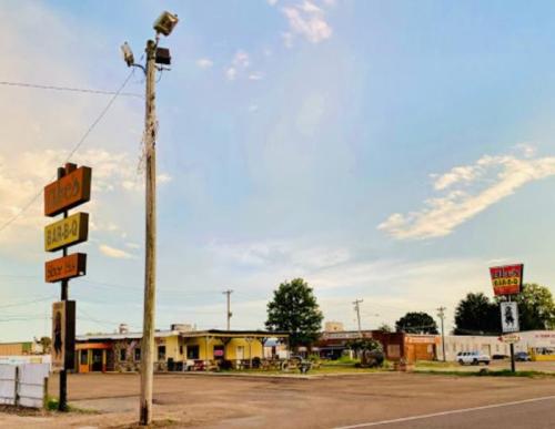 A BBQ restaurant with outdoor seating, surrounded by a parking lot and signs, under a clear sky.