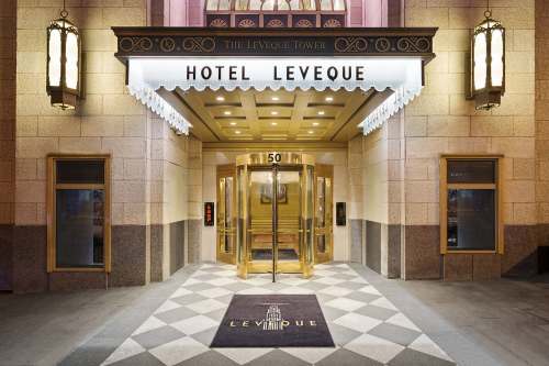 Entrance of Hotel LeVeque, featuring a revolving door and elegant signage, with a patterned floor mat.