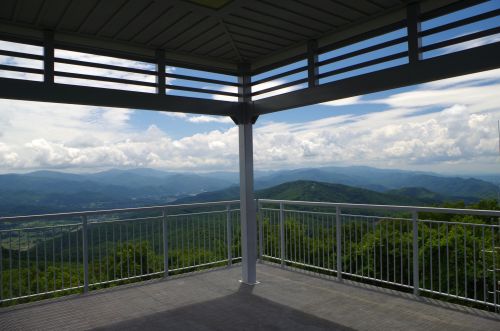 A scenic view from a gazebo overlooking lush green mountains and a cloudy sky.