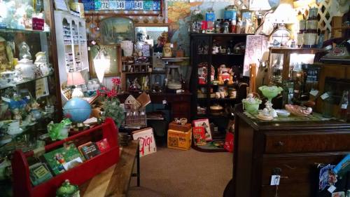 A cozy antique shop filled with various vintage items, including lamps, glassware, and decorative pieces.