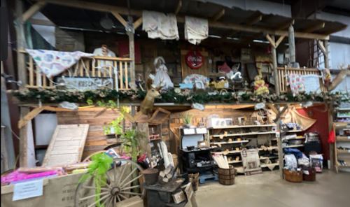 A rustic display featuring wooden shelves, decorations, and various vintage items in a market setting.