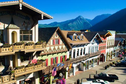 Charming alpine-style buildings line a street, with mountains in the background and clear blue skies above.