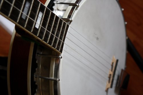 Close-up of a banjo neck and strings, showcasing the instrument's wooden body and metal hardware.