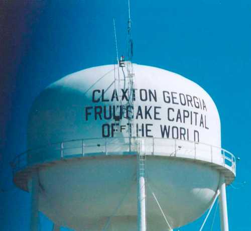 Water tower with the text "Claxton Georgia Fruitcake Capital of the World" against a clear blue sky.