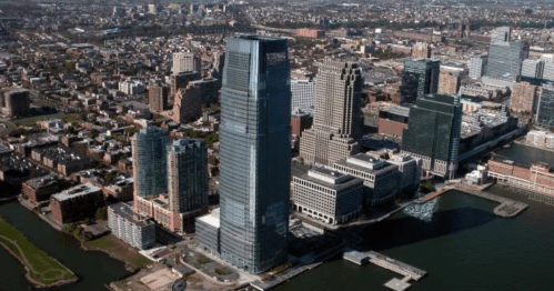 Aerial view of a modern city skyline featuring tall buildings near a waterfront.