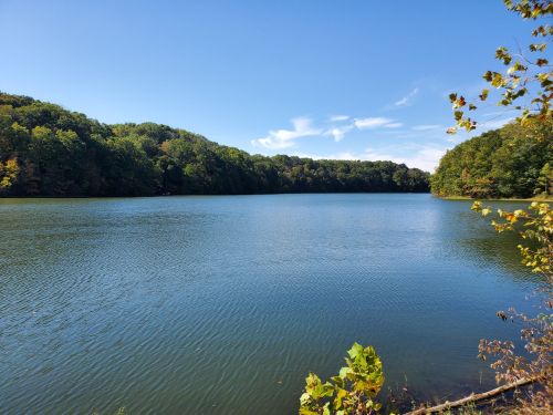 A serene lake surrounded by lush green hills under a clear blue sky.