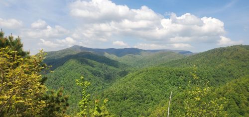 A panoramic view of lush green mountains under a partly cloudy sky.