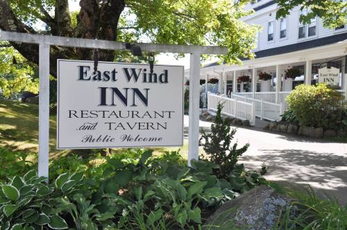 Sign for East Wind Inn Restaurant and Tavern, surrounded by greenery, with a welcoming atmosphere.
