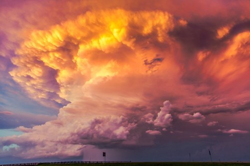 Dramatic sunset clouds in vibrant shades of orange, pink, and purple, with a silhouette of a distant horizon.