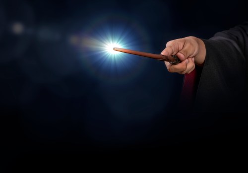 A hand holding a magic wand, emitting a bright light against a dark background.