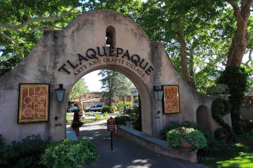 Entrance to Tlaquepaque Arts and Crafts Village, featuring a decorative arch and lush greenery.