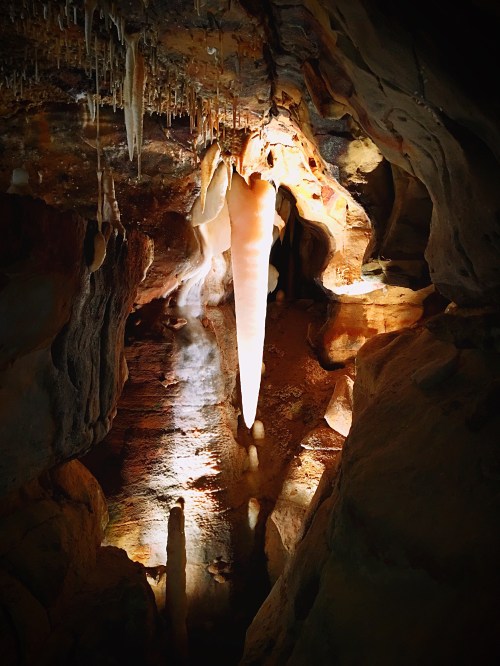 A stunning cave interior featuring stalactites and stalagmites, illuminated by soft light, creating a mystical atmosphere.