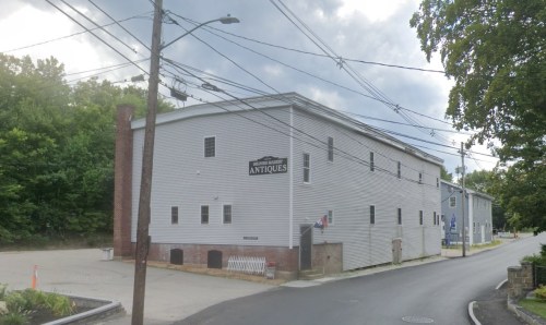 A gray building with a sign reading "Antiques," located at a street corner with power lines overhead.