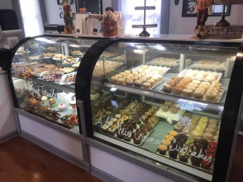 A display case filled with a variety of colorful cupcakes and desserts in a cozy bakery setting.