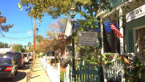 A charming street scene featuring historic buildings, a sign for "History," and parked cars under a clear blue sky.