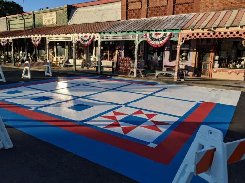 A colorful painted game board on a street, with vintage shops and festive decorations in the background.