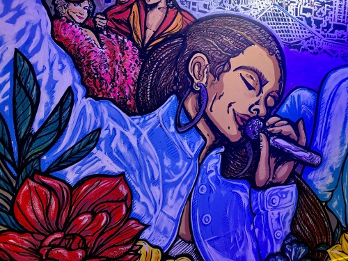 A vibrant mural featuring a woman singing into a microphone, surrounded by colorful flowers and artistic elements.