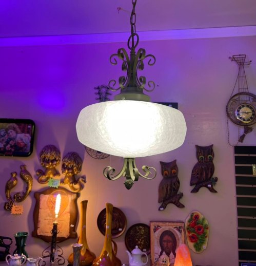A decorative pendant light hangs from the ceiling, surrounded by various wall art and vintage decor.