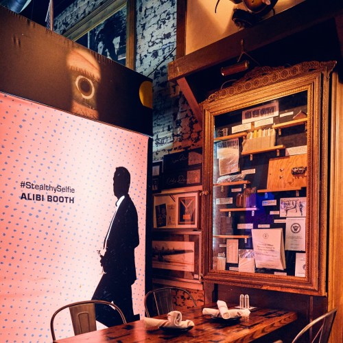 A cozy restaurant interior featuring an alibi booth backdrop and a wooden table set for dining.