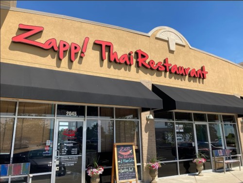 Exterior of Zapp! Thai Restaurant, featuring a sign and large windows, with a chalkboard menu outside.