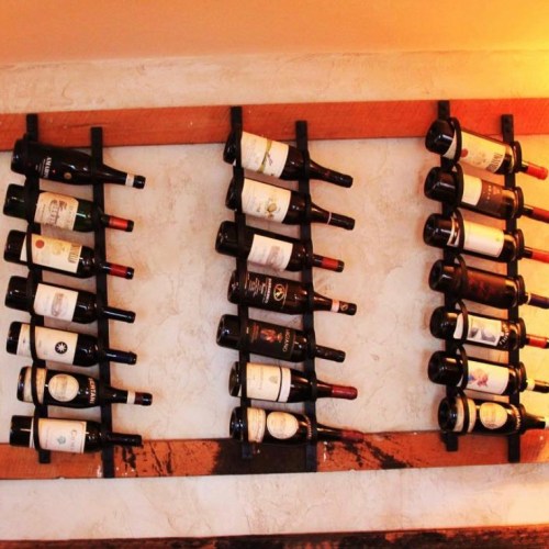 A wall-mounted wine rack displaying various bottles of wine with labels visible.