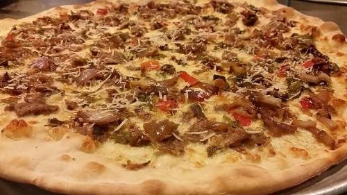 A close-up of a pizza topped with meat, vegetables, and cheese on a golden crust.