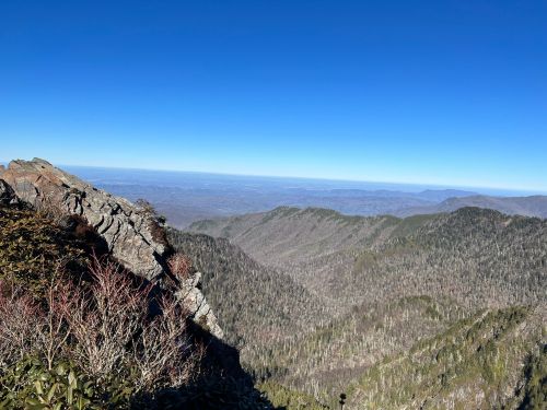 A panoramic view of rugged mountains and valleys under a clear blue sky.