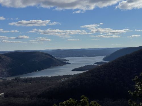A scenic view of a river winding through mountains under a partly cloudy sky.