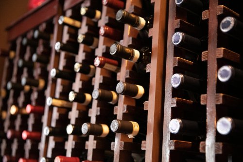 A wooden wine rack filled with various bottles of wine, showcasing different colors and labels.