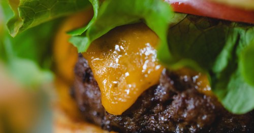 A close-up of a juicy cheeseburger with fresh lettuce and tomato at Murphy's Pub and Grill.