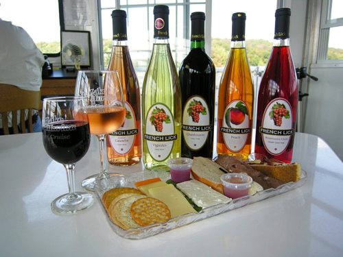 A selection of wines and a cheese platter with crackers, served on a table in a bright, airy setting.