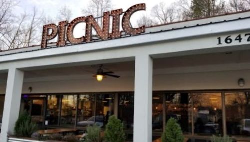 A restaurant named "PICNIC" with a marquee sign, featuring large windows and greenery in front.