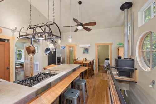 Bright kitchen with a wooden bar, modern appliances, dining area, and large windows for natural light.