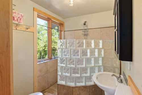 Bright bathroom featuring a glass block shower, modern fixtures, and natural light from large windows.