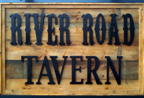 Sign featuring the text "RIVER ROAD TAVERN" in bold black letters on a wooden background.