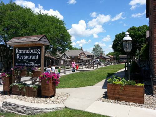 A sunny day at Ronneburg Restaurant, featuring a landscaped path, flowers, and visitors strolling in a quaint setting.