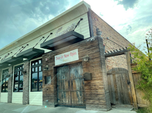 A rustic drive-in restaurant with a wooden door and a sign that says "Drive-in Now Open."