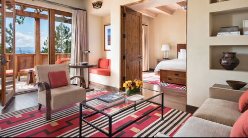 Cozy hotel room with modern decor, featuring a seating area, large windows, and a view of nature.