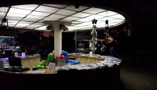 A dimly lit gift shop with a circular counter, displaying various merchandise and colorful items on the shelves.