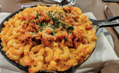 A cast-iron skillet filled with creamy macaroni and cheese topped with breadcrumbs and herbs.