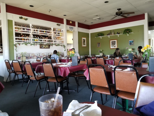 Interior of a restaurant with green walls, tables set for dining, and patrons seated at tables.